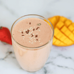 Vegan recipe book cover featuring a vibrant strawberry mango protein smoothie in a glass with fresh fruit and green leaves.
