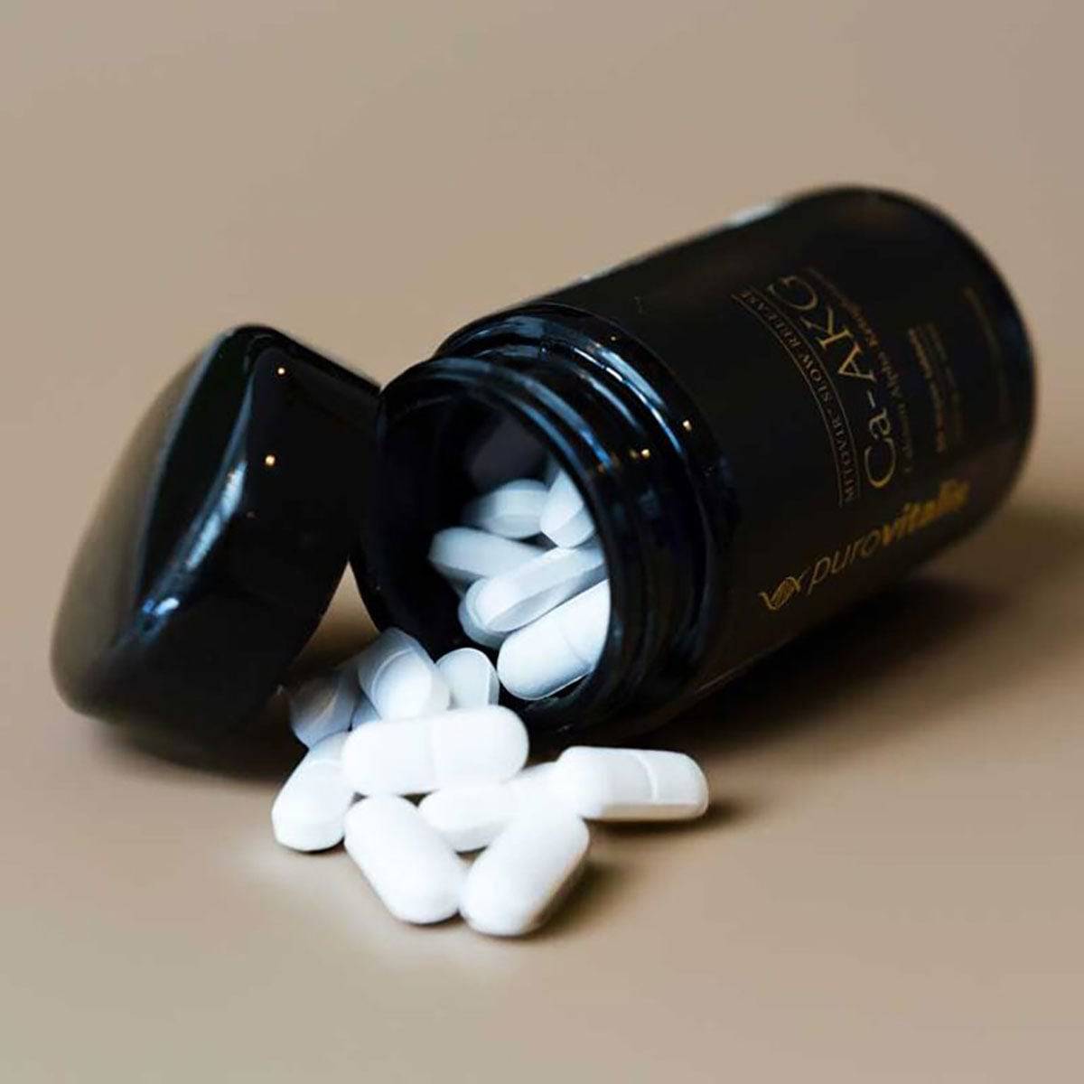 Herbalistas Slow Release Calcium AKG supplement tablets, 60 count, showing small white tablets in a blister pack.